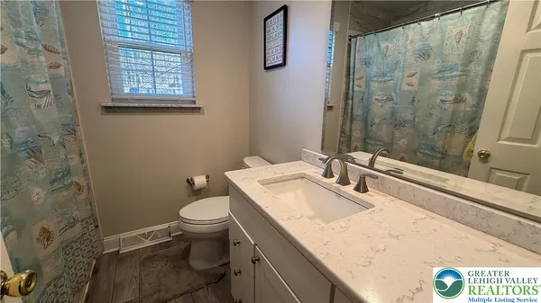 a bathroom with a granite countertop sink a toilet a mirror and shower