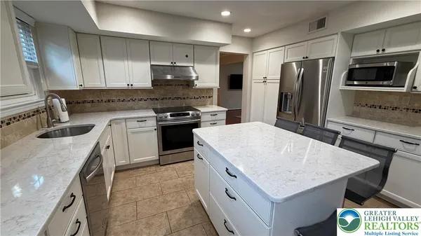 a kitchen with stainless steel appliances granite countertop a sink stove microwave and refrigerator