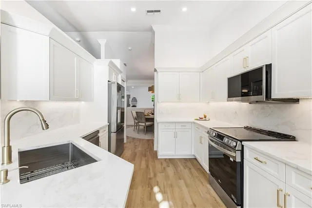 a kitchen with stainless steel appliances granite countertop a sink and a stove top oven with wooden floor