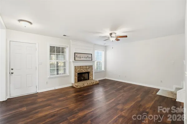 a view of an empty room with a fireplace and wooden floor