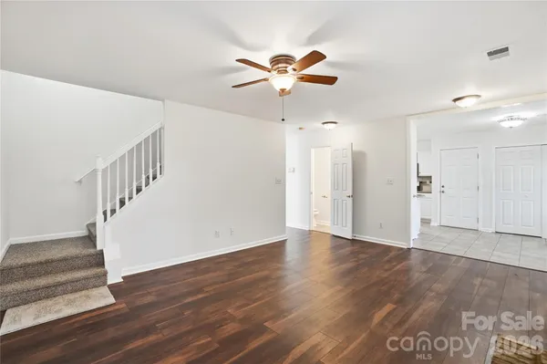 a view of an empty room with wooden floor and a ceiling fan