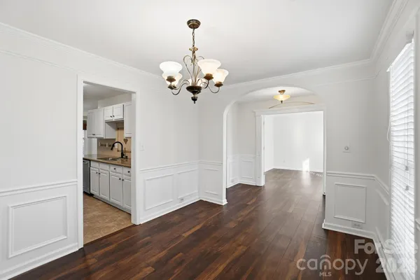 a view of a hallway with wooden floor and a kitchen