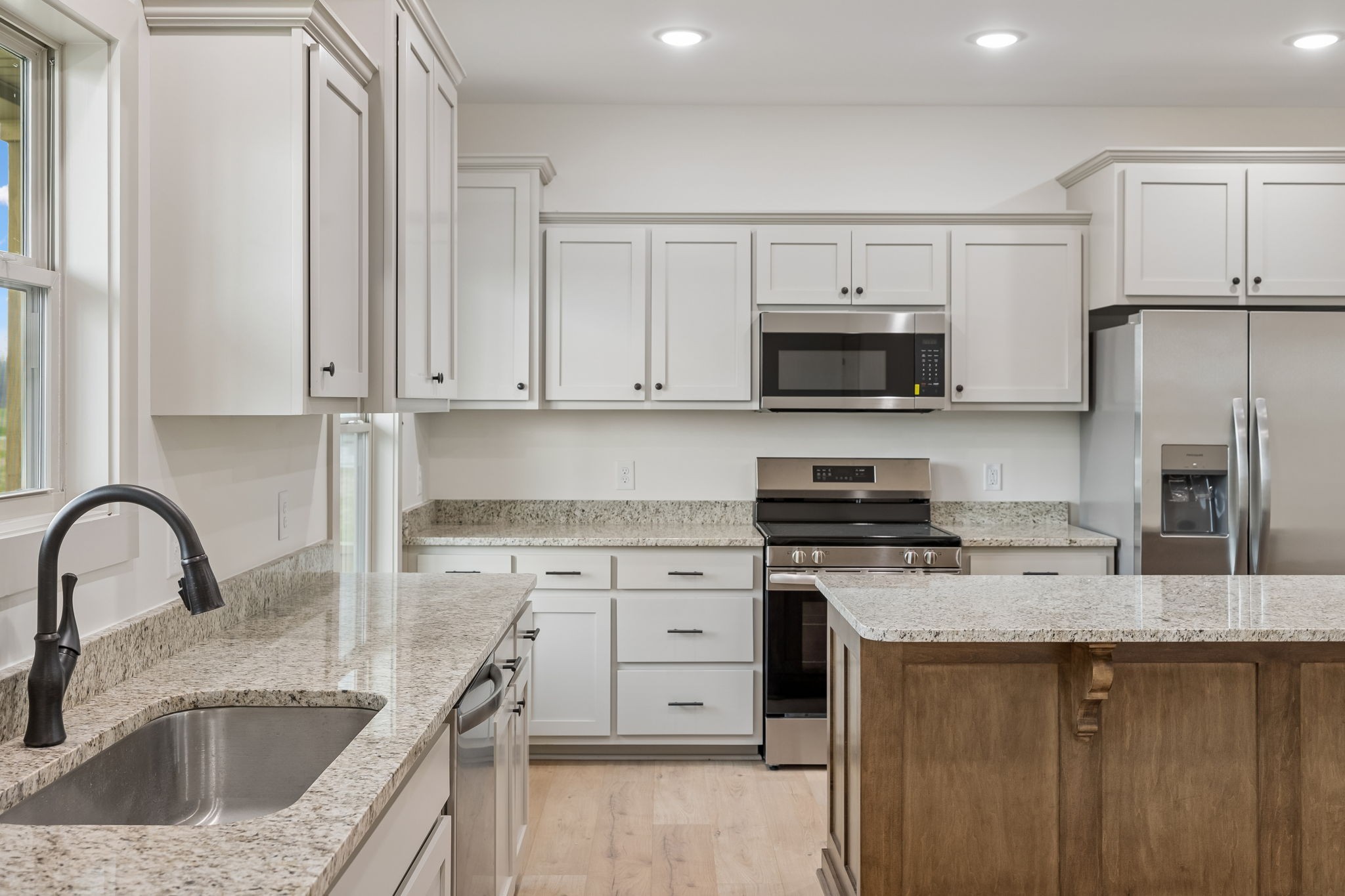 a kitchen with stainless steel appliances granite countertop a stove a sink a refrigerator and a microwave