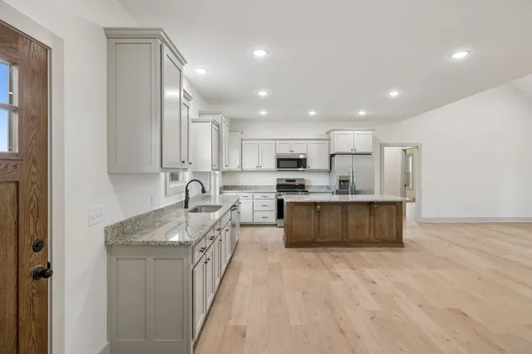 a large kitchen with stainless steel appliances granite countertop a large counter top a stove a sink and a refrigerator