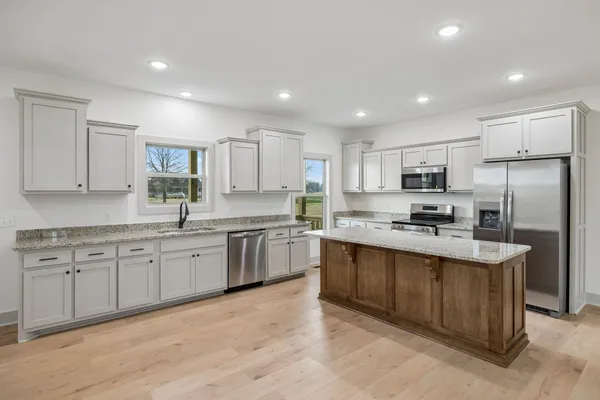 a large kitchen with stainless steel appliances lots of counter space sink and a refrigerator