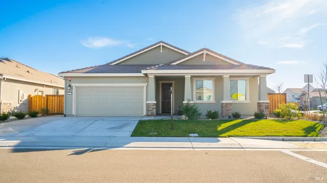 a view of a house with a yard and large tree