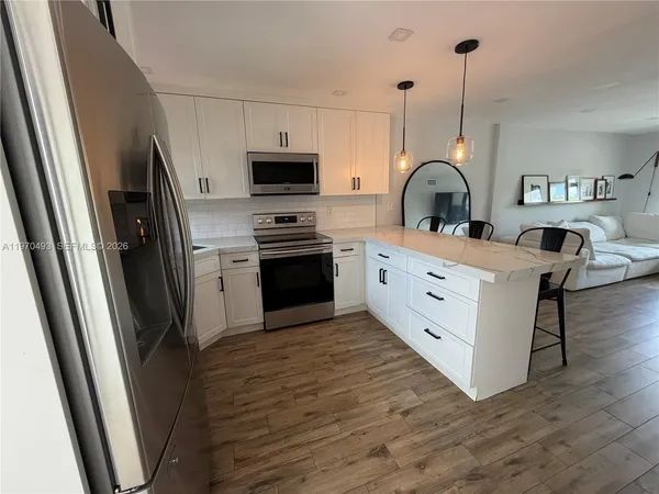 a kitchen with stainless steel appliances a stove refrigerator sink and wooden floor