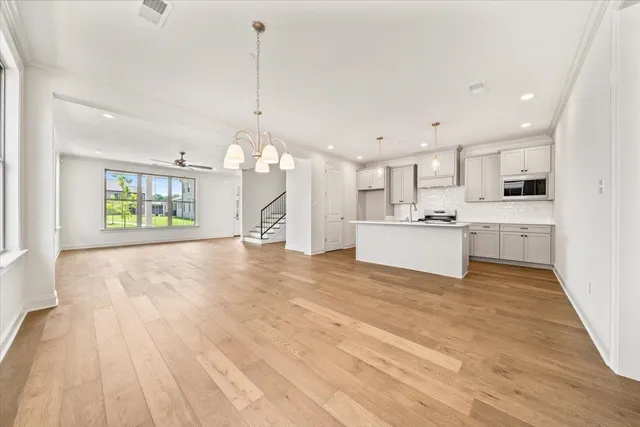 a view of a kitchen with kitchen island white cabinets and stainless steel appliances
