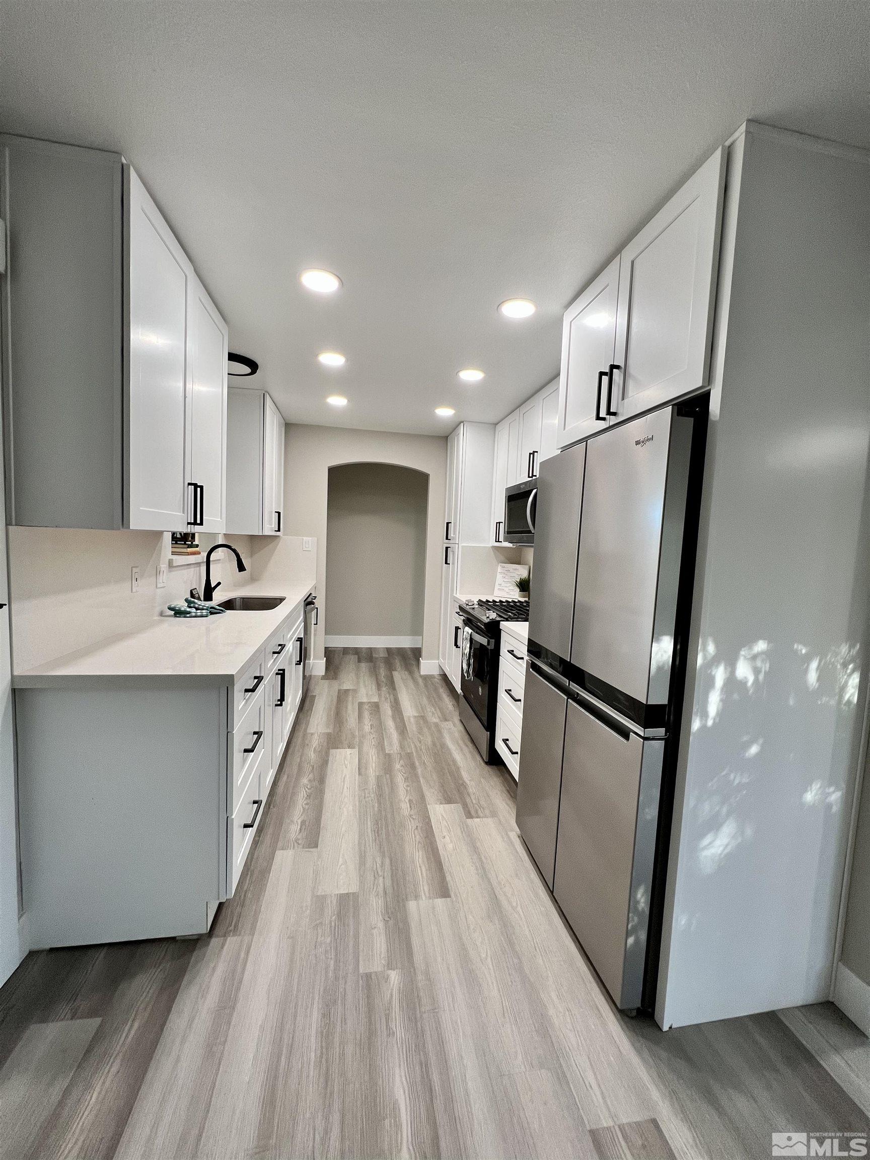 4475 Apollo Drive Carson City, NV 89706 - Photo 22 of 40 a kitchen with stainless steel appliances a refrigerator sink and wooden floor