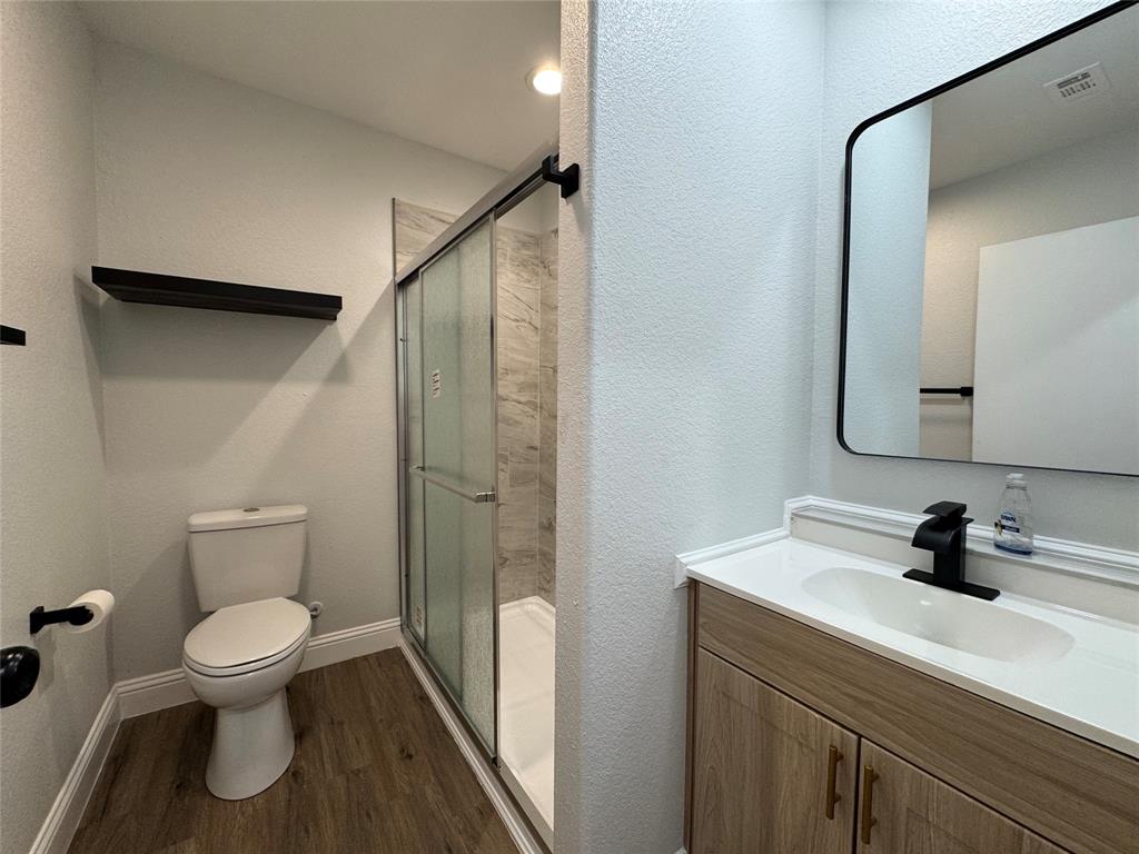 2909 Alexander Avenue Waco, TX 76708 - Photo 21 of 27 Full bathroom featuring a shower stall, dark wood-style flooring, vanity, and a textured wall