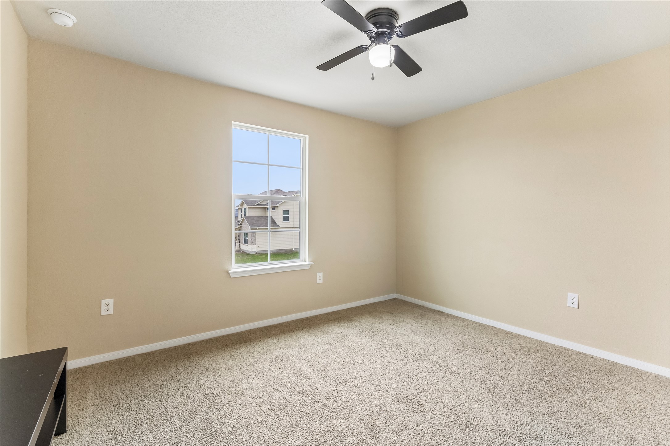 14409 Estuary Road Manor, TX 78653 - Photo 16 of 24 Carpeted room featuring a single window with grids, a ceiling fan with light fixture, and neutral-toned walls
