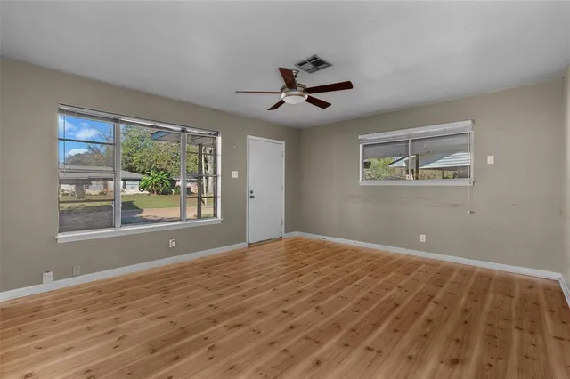a view of empty room with wooden floor and fan
