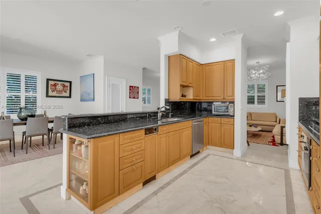 a kitchen with stainless steel appliances granite countertop a stove top oven a sink a dining table and chairs with wooden floor