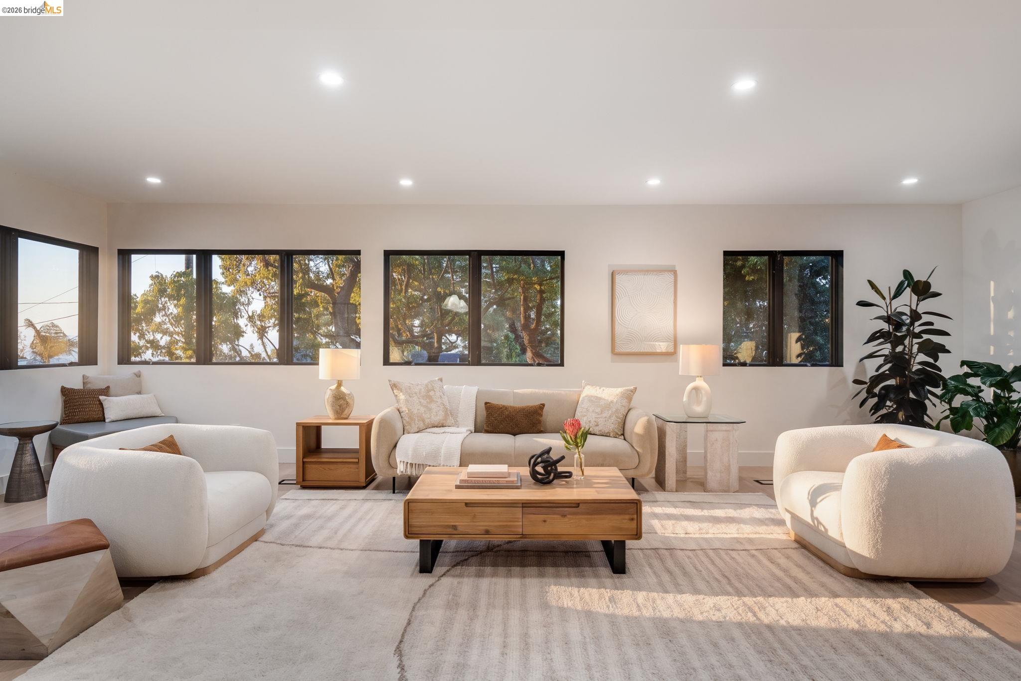 1409 Scenic Avenue Berkeley, CA 94708 - Photo 19 of 28 Spacious living area featuring recessed lighting, a window seat with cushioned seating, and multiple black-framed windows overlooking mature trees