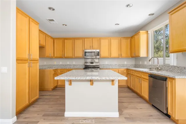 a view of kitchen island with granite countertop cabinets and refrigerator