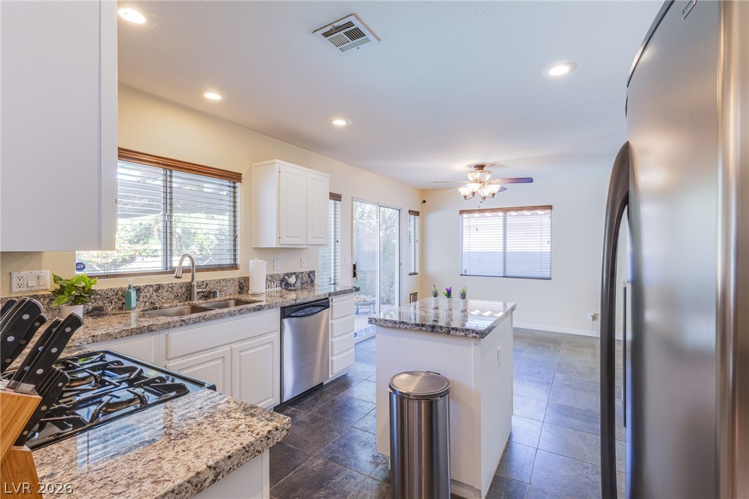 253 Camelback Ridge Avenue Henderson, NV 89012 - Photo 13 of 26 Polished granite countertops complement white cabinetry and durable tile flooring in this open layout.