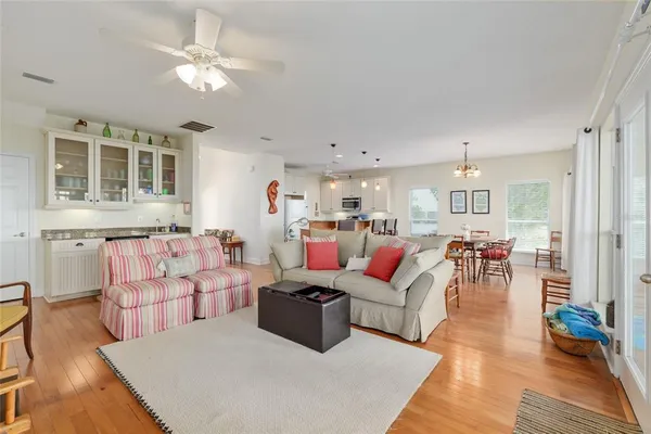 a open kitchen with stainless steel appliances granite countertop a stove top oven a sink dishwasher a dining table and chairs with wooden floor
