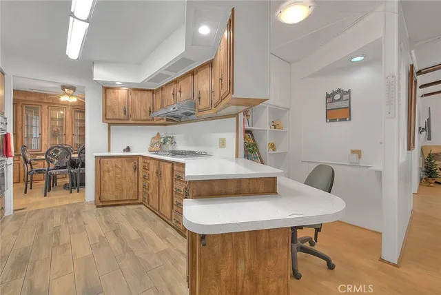 a living room with stainless steel appliances furniture a dining table wooden floor and a kitchen view