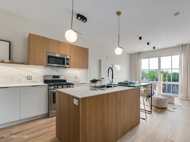 a kitchen with stainless steel appliances a stove a sink a center island and a window