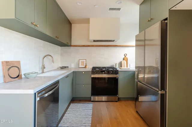 a kitchen with stainless steel appliances granite countertop a sink a stove a refrigerator and cabinets