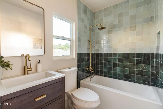 a bathroom with a sink a toilet a mirror a bathtub and shower