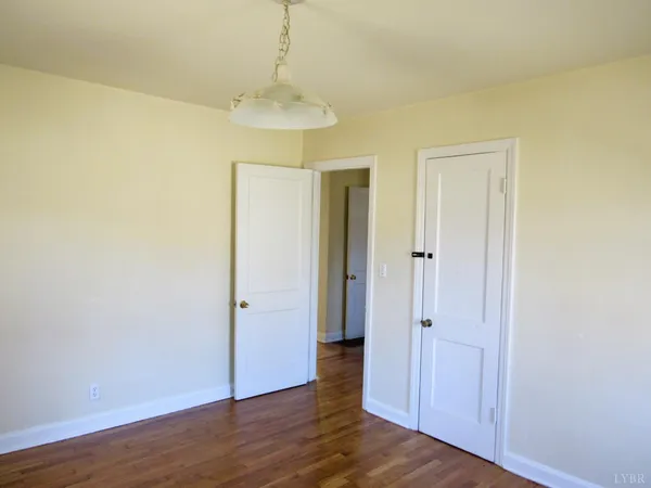 an empty room with wooden floor and hallway