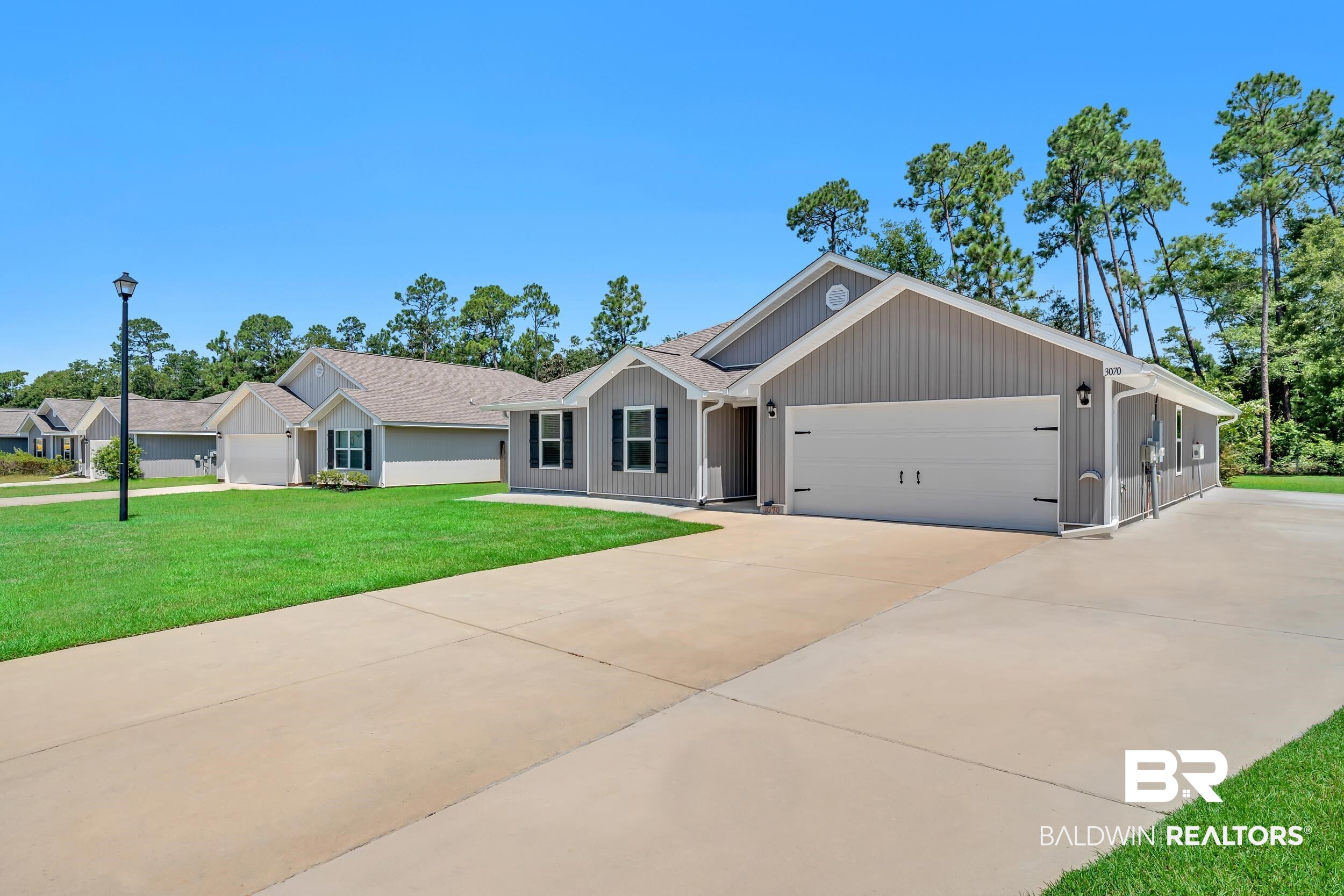 3070 Camino Real Loop Lillian, AL 36549 - Photo 3 of 46 Modern single-story residence with a gray vertical siding exterior and a two-car garage