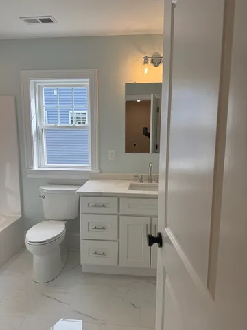 a bathroom with a sink toilet a mirror and window
