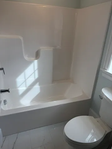 a white toilet sitting next to a bath tub