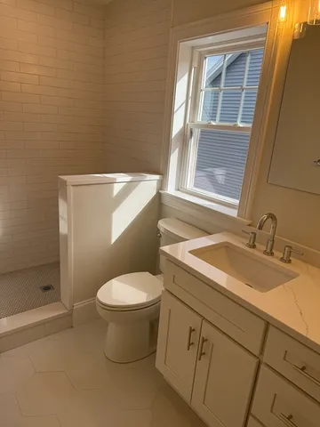 a bathroom with a granite countertop toilet sink and mirror