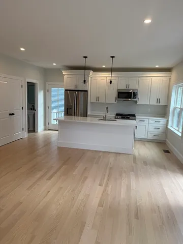a large kitchen with a wooden floor and stainless steel appliances