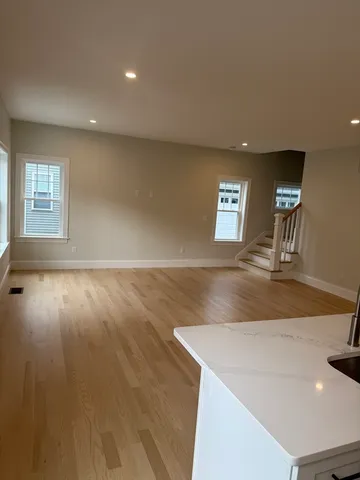 a view of an empty room with window and wooden floor