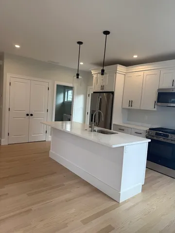 a kitchen with kitchen island a counter top space a sink stainless steel appliances and cabinets