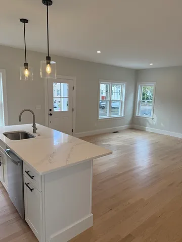 a view of a kitchen stove a sink and dishwasher with wooden floor
