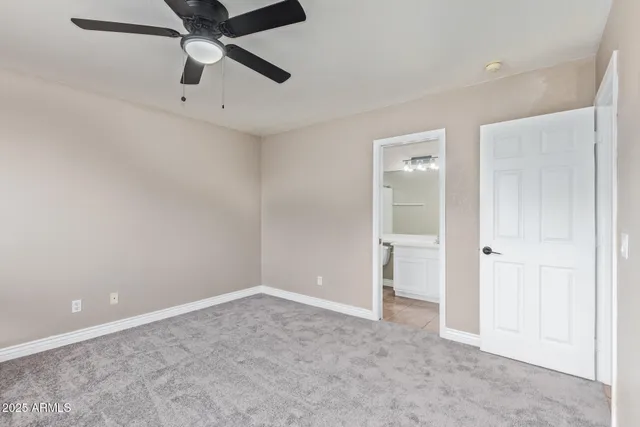 an empty room with a ceiling fan and carpet