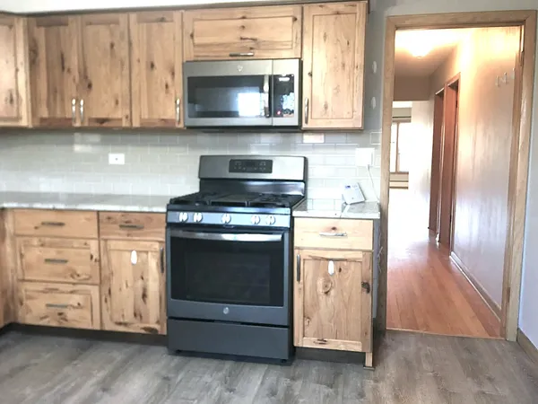 a kitchen with stainless steel appliances granite countertop a stove a microwave and a white wooden cabinets