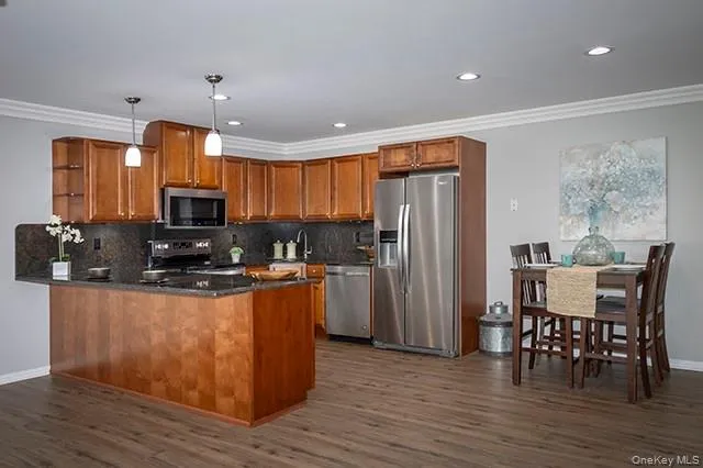 a kitchen with stainless steel appliances granite countertop a refrigerator a stove top oven a sink dishwasher a dining table and chairs with wooden floor
