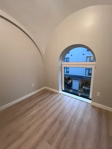 a view of empty room with wooden floor and fireplace