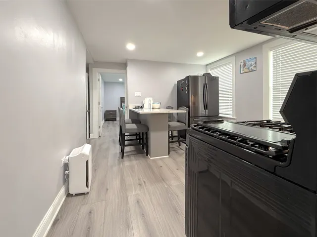 a kitchen with stainless steel appliances granite countertop a stove refrigerator and chairs