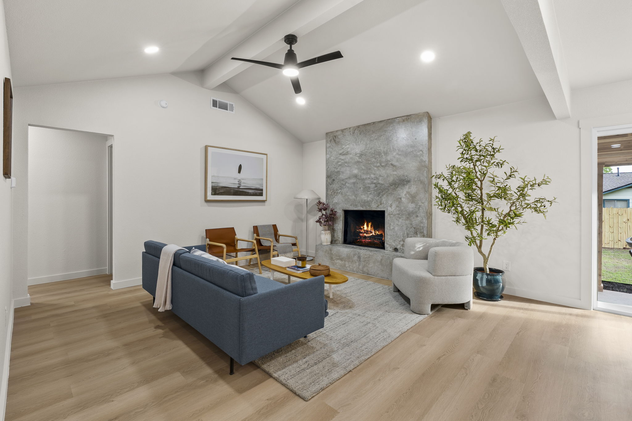 2107 Cindy Lane Austin, TX 78727 - Photo 5 of 33 Spacious living area featuring vaulted ceilings with exposed beams, LVP flooring, a modern ceiling fan, recessed lighting, and a large fireplace with a textured stone surround