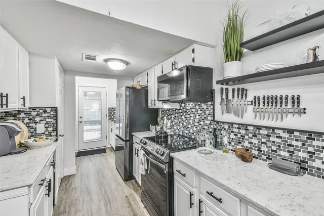a kitchen with stainless steel appliances kitchen island granite countertop a sink stove and refrigerator