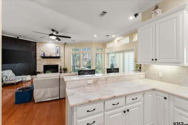 a kitchen with granite countertop a stove a sink and a refrigerator with white cabinets
