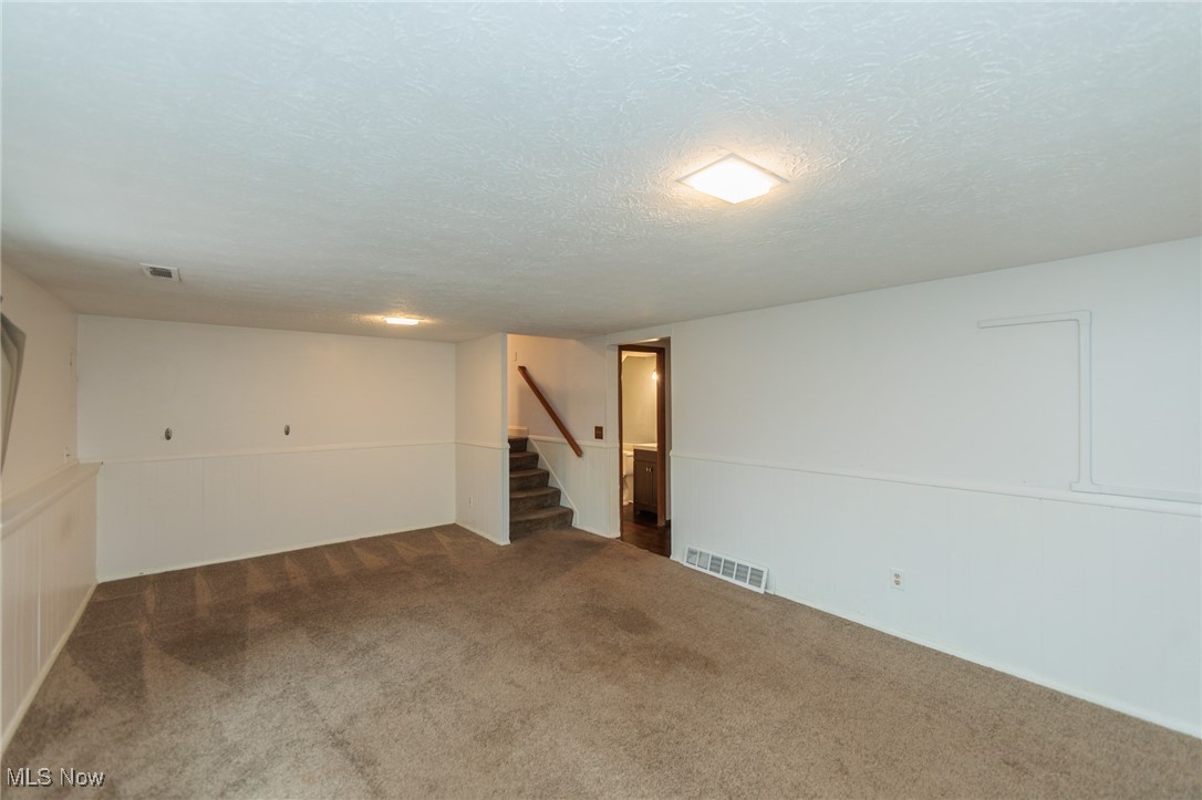 28013 Knickerbocker Road Bay Village, OH 44140 - Photo 28 of 38 Family room featuring a textured ceiling, carpet, and stairs