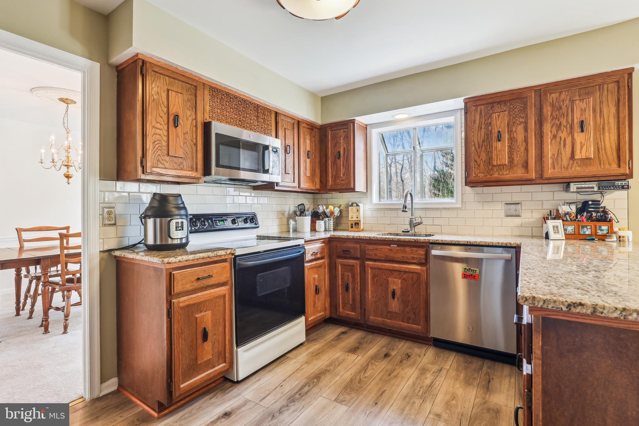7122 Rolling Forest Avenue Springfield, VA 22152 - Photo 13 of 58 a kitchen with stainless steel appliances granite countertop a stove a sink dishwasher and a microwave oven with wooden cabinets