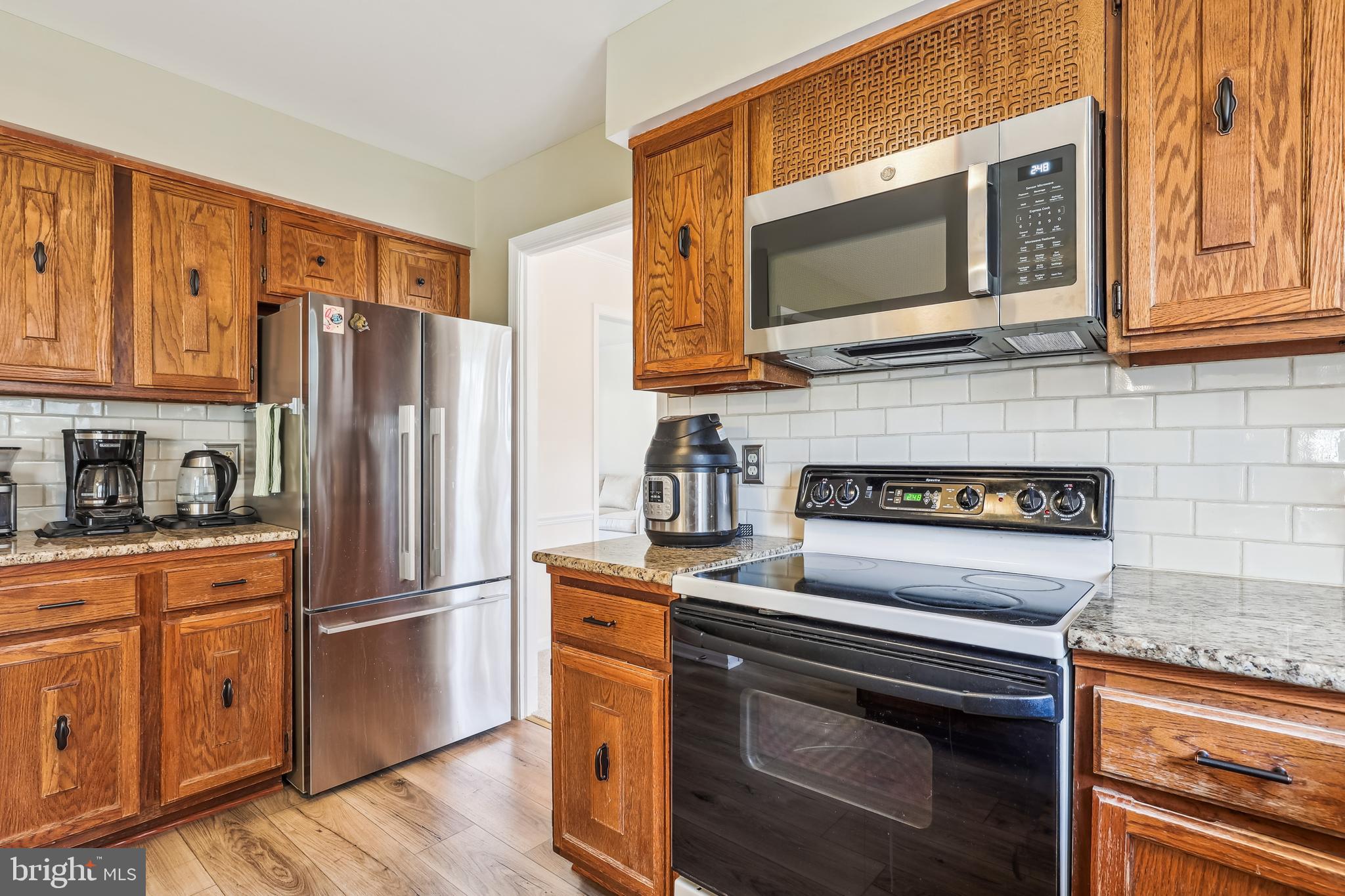 7122 Rolling Forest Avenue Springfield, VA 22152 - Photo 14 of 58 a kitchen with stainless steel appliances granite countertop a refrigerator stove and microwave