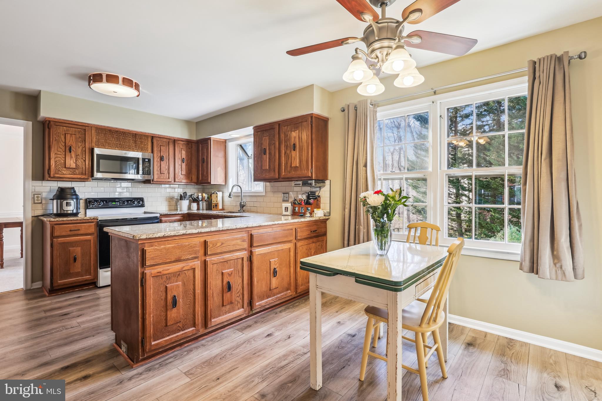 7122 Rolling Forest Avenue Springfield, VA 22152 - Photo 15 of 58 a kitchen with stainless steel appliances granite countertop a stove top oven a refrigerator a dining table and chairs with wooden floor