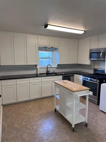 a kitchen with granite countertop white cabinets and white stainless steel appliances