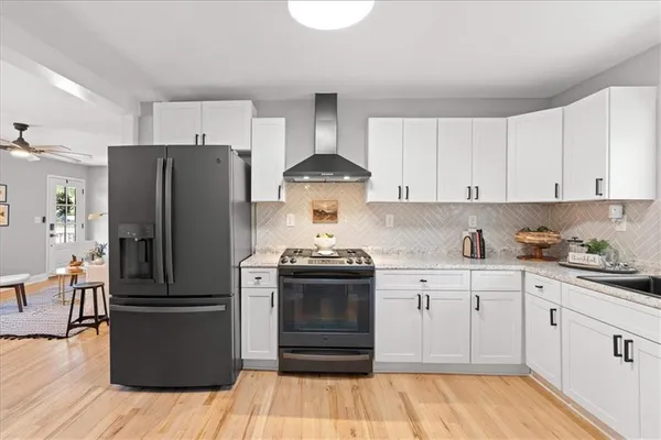 a kitchen with a refrigerator stainless steel appliances wooden floor and cabinets