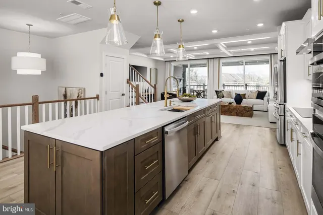 a large kitchen with kitchen island a sink a counter top space stainless steel appliances and a chandelier