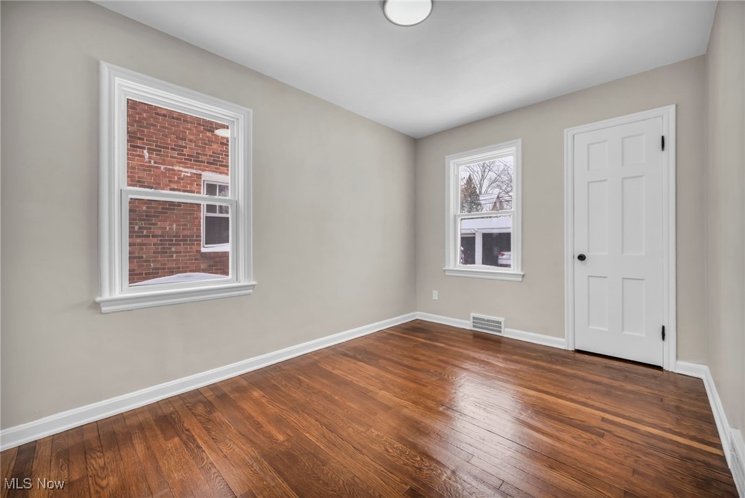 13614 Cedar Road Cleveland, OH 44118 - Photo 13 of 46 Empty room with dark wood-style floors, visible vents, and baseboards